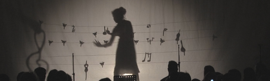 Théâtre d’ombres sur un décor de notes de musique, devant le public